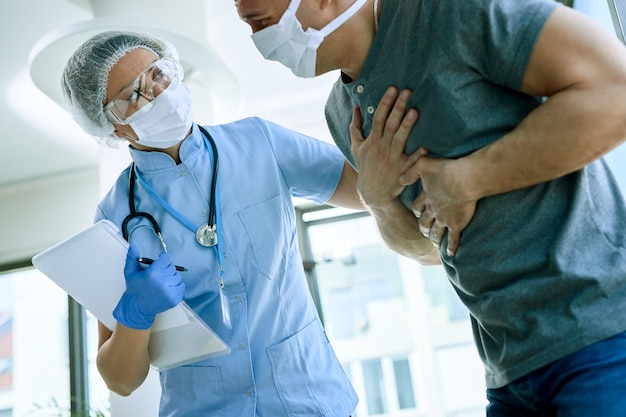 Foto gratuita doctora con un paciente que se queja de dolor en el pecho durante la epidemia de coronavirus