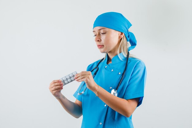 Doctora con paquete de pastillas en uniforme azul