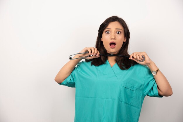 Doctora poniéndose el estetoscopio alrededor de su cuello sobre fondo blanco. Foto de alta calidad