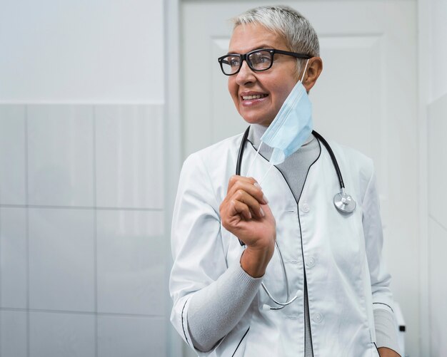 Doctora poniéndose una máscara médica con espacio de copia