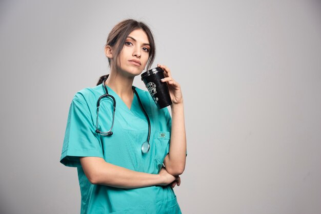 Doctora posando con taza de café en gris