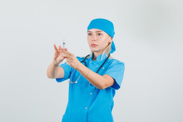 Doctora preparando jeringa para inyección en uniforme azul