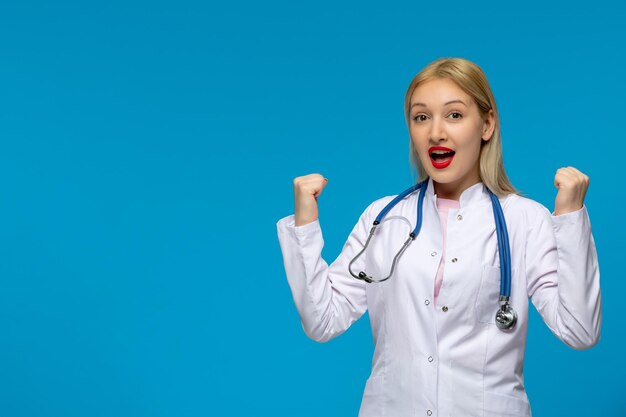 Doctora rubia del día mundial del médico con el estetoscopio en la bata de laboratorio