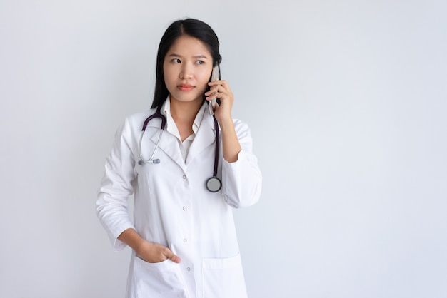 Doctora seria hablando por teléfono inteligente