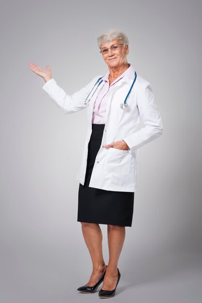 Doctora sonriente apuntando al espacio de la copia