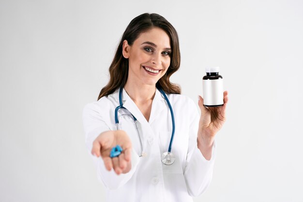 Doctora sonriente sosteniendo una botella de píldoras