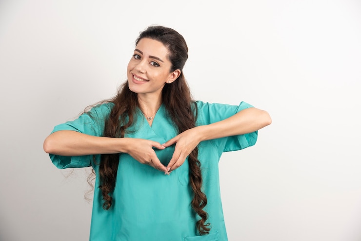 Foto gratuito doctora sonriente en uniforme mostrando las manos en forma de corazón.