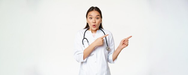 Una doctora sorprendida dice wow apuntando a la derecha y mirando asombrada con descuentos en la clínica mostrando w