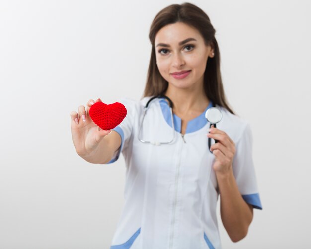 Doctora sosteniendo un corazón de felpa y un estetoscopio