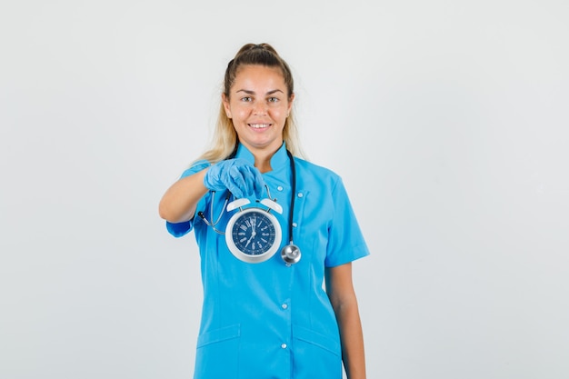 Doctora sosteniendo despertador en uniforme azul