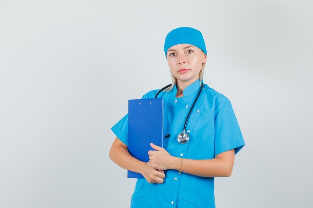 Doctora sosteniendo portapapeles en uniforme azul