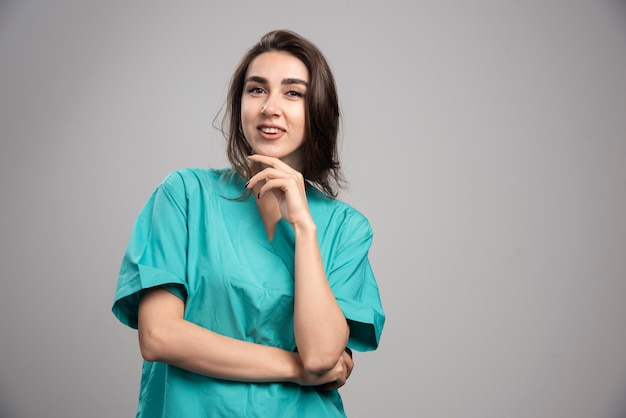 Doctora sosteniendo su barbilla y mirando a cámara. Foto de alta calidad