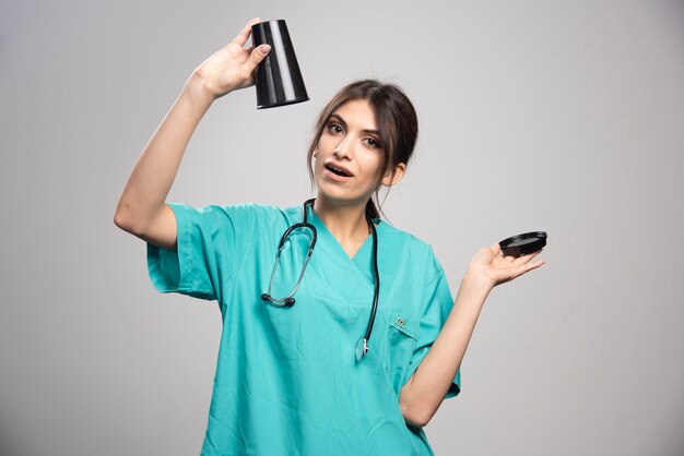 Doctora sosteniendo una taza de café en gris