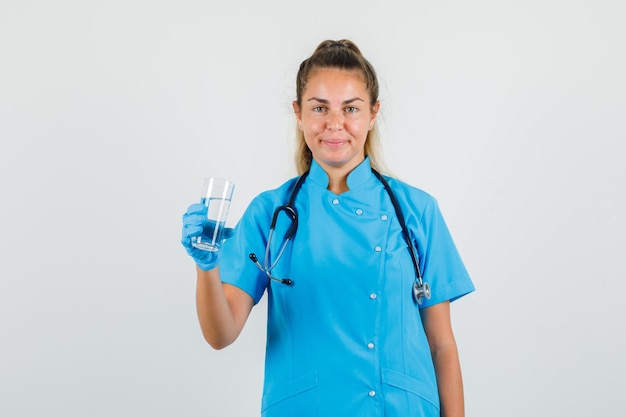 Doctora sosteniendo un vaso de agua en uniforme azul