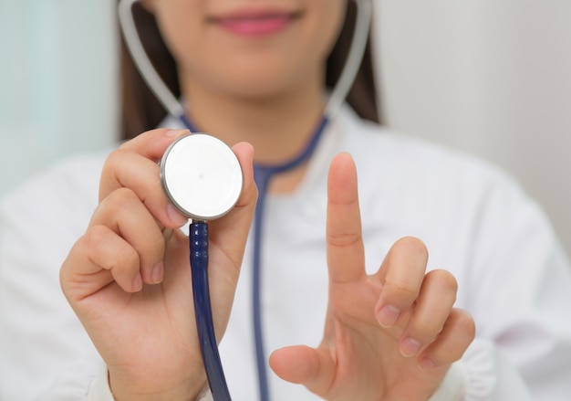 Doctora sujetando un estetoscopio y enseñando el dedo índice