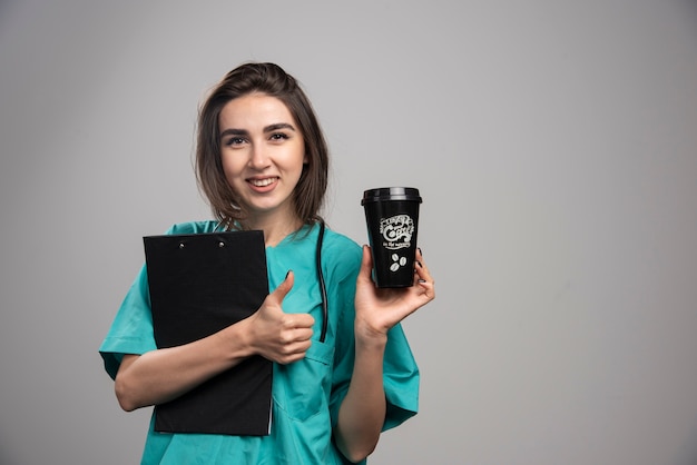 Doctora con taza de café y portapapeles.