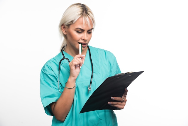 Doctora tratando de escribir algo en el portapapeles con lápiz sobre fondo blanco. Foto de alta calidad