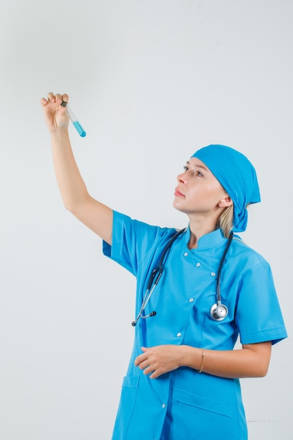 Doctora con tubo de ensayo en uniforme azul