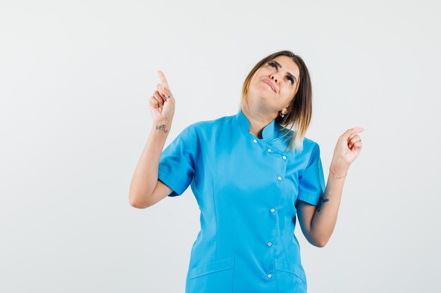 Doctora en uniforme azul mirando hacia arriba y mirando esperanzado