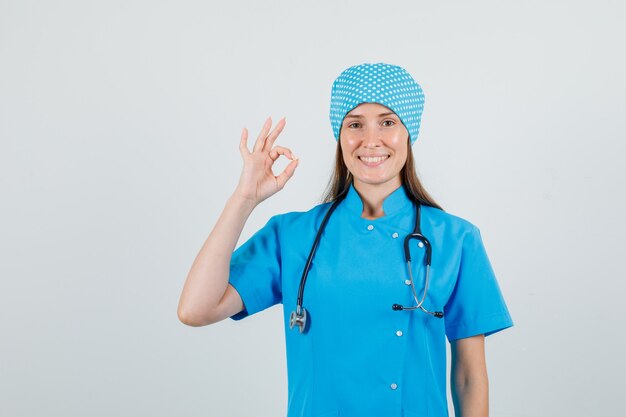 Doctora en uniforme azul mostrando gesto ok y mirando alegre