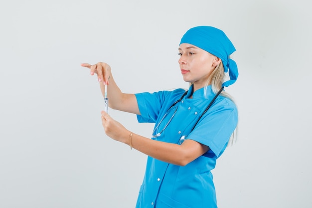 Doctora en uniforme azul preparando jeringa para inyección