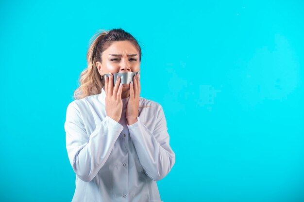 Doctora en uniforme blanco cubriendo su boca.