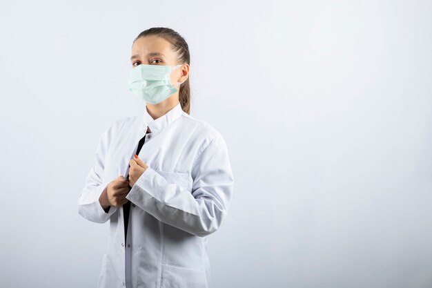 Doctora en uniforme blanco con una máscara médica