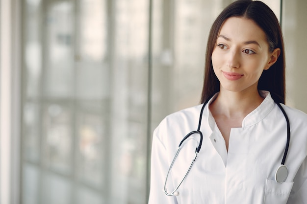 Doctora en uniforme blanco de pie en una sala