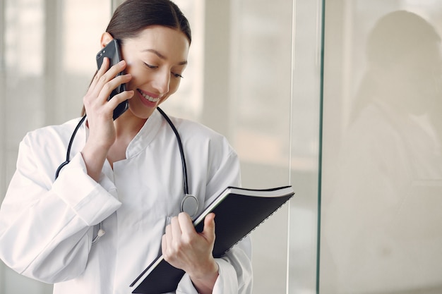 Doctora en uniforme blanco de pie en una sala