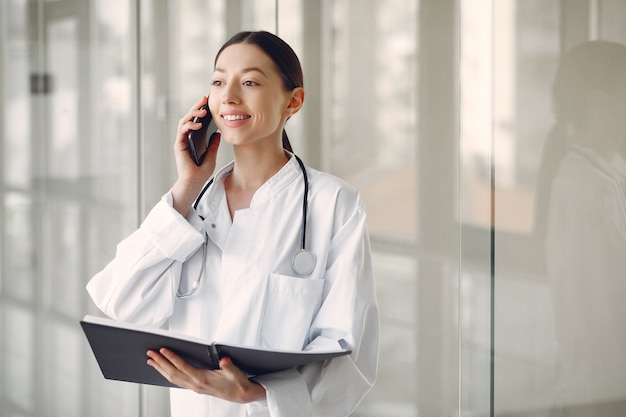 Doctora en uniforme blanco de pie en una sala