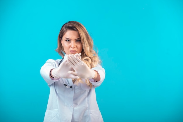 Doctora en uniforme blanco previniendo y deteniendo algo.