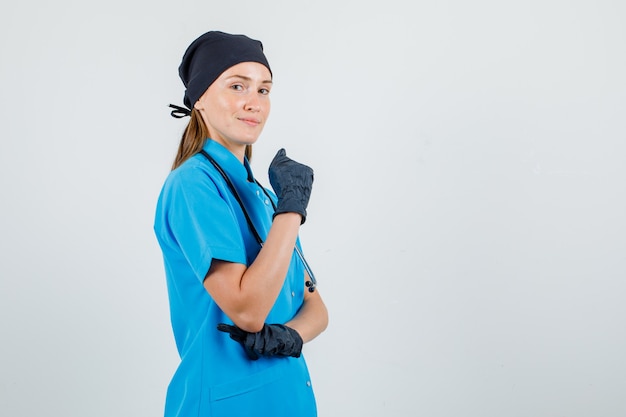 Doctora en uniforme, guantes posando mientras mantiene el puño levantado y parece seguro.