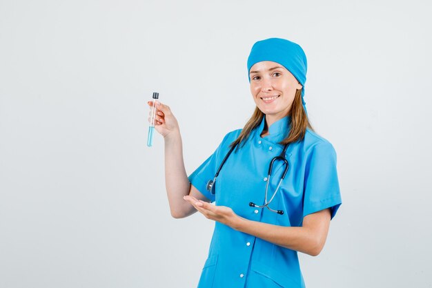 Doctora en uniforme mostrando tubo de ensayo y mirando alegre