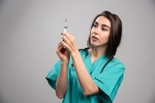 Foto gratuita doctora en uniforme preparando jeringa.