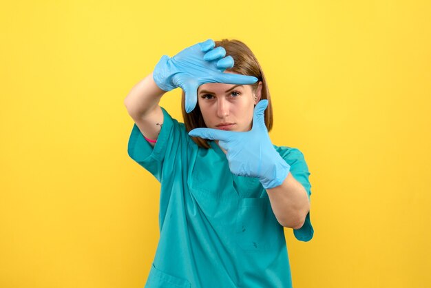 Doctora vista frontal con guantes azules en el espacio amarillo