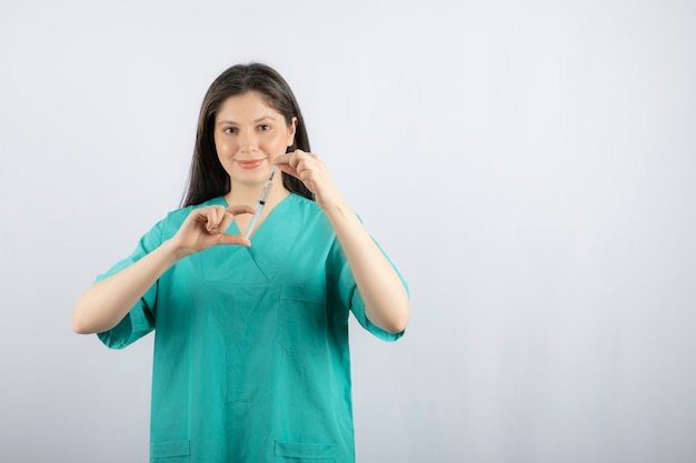 Doctora vistiendo uniforme verde con jeringa en blanco.