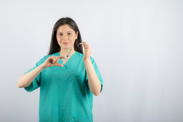 Doctora vistiendo uniforme verde con jeringa en blanco.