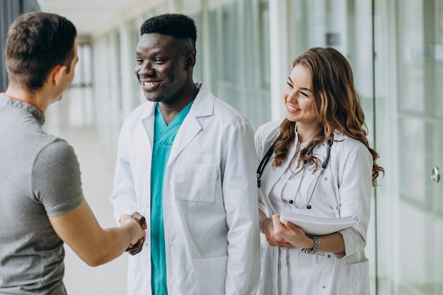 Foto gratuita doctores dándose la mano con el paciente, de pie en el pasillo del hospital.