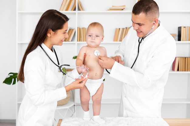 Doctores escuchando bebé con estetoscopio