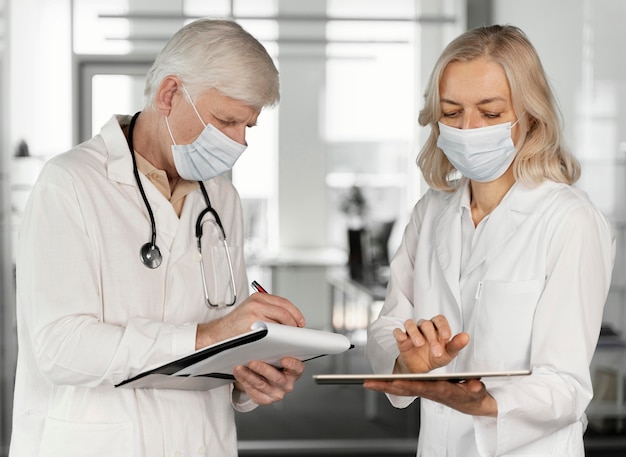 Foto gratuita doctores con máscaras médicas hablando