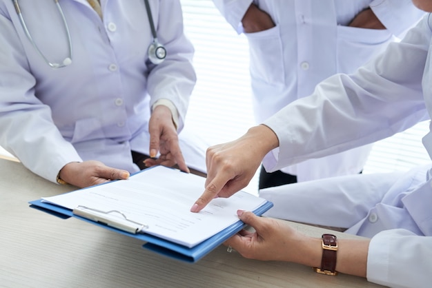 Doctores recortados discutiendo documentos médicos en equipo
