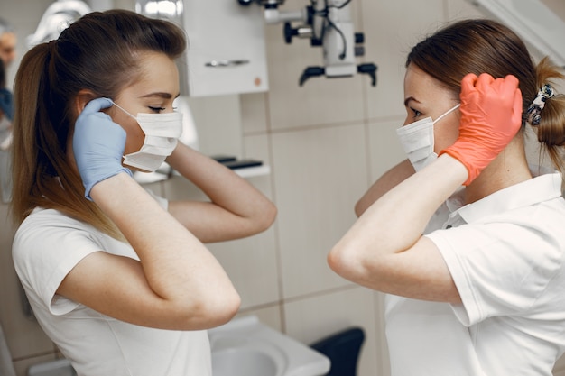 Doctores en uniforme especial Los dentistas usan máscaras protectoras Las niñas se miran entre sí