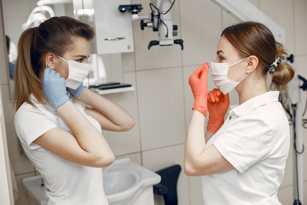 Doctores en uniforme especial Los dentistas usan máscaras protectoras Las niñas se miran entre sí