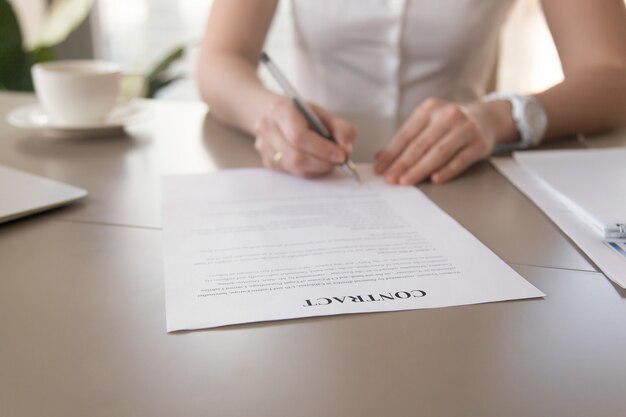 Documento de firma de la empresaria, manos femeninas que ponen la firma, foco en contrato