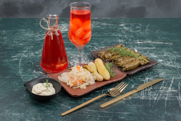 Dolma con vaso de jugo y crema agria en la pared de mármol.