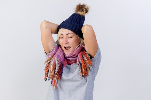 Foto gratuita dolor joven rubia enferma mujer eslava vistiendo gorro y bufanda de invierno pone las manos en la cabeza detrás aislado en la pared blanca con espacio de copia