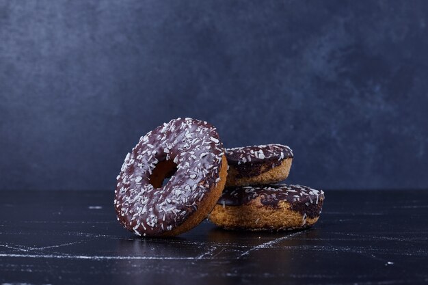 Donas de chocolate aisladas sobre superficie negra.