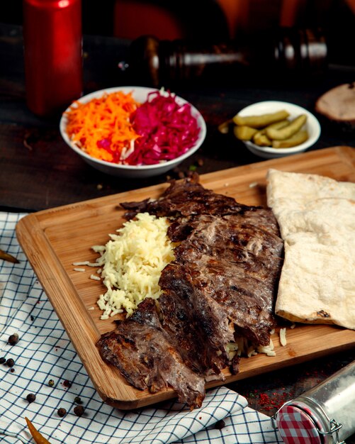 Doner de carne con arroz y lavash sobre tabla de madera