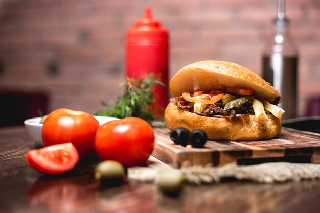 Doner de cordero en pan con pepinillos encurtidos papas fritas tomate servido con salsa de tomate y mayonesa