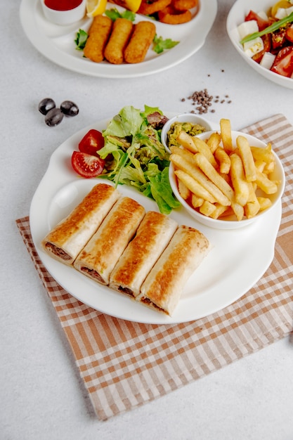 Doner envuelto en lavash con papas fritas y ensalada fresca en un plato